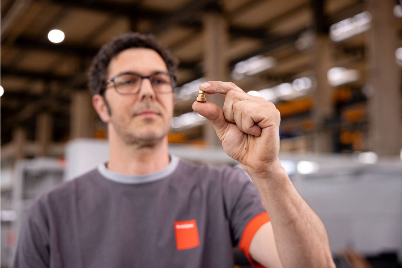 A man wearing glasses inspects a tiny item, focusing on after-sales service and support.