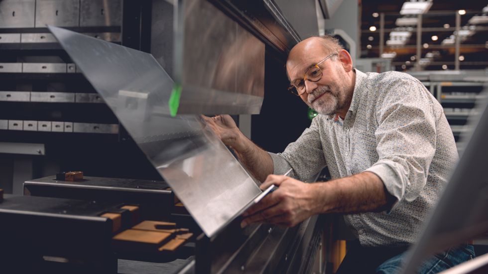 Man with glasses examines a bent sheet metal